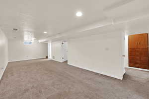 Empty room with light carpet and recessed lighting