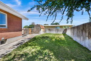 Fenced backyard featuring a storage shed