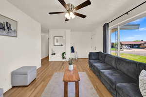 Living room featuring light wood-style flooring, ceiling fan, and a textured ceiling