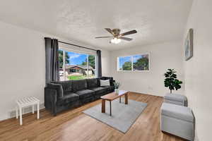 Living room featuring light wood finished floors, a textured ceiling, and a ceiling fan