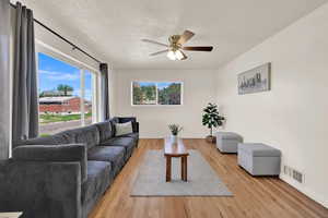 Living room with light wood-style floors, a textured ceiling, and ceiling fan