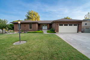 Ranch-style home with an attached garage, brick siding, a front yard, and driveway
