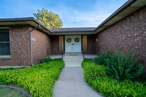 Property entrance with brick siding, covered porch, and french doors