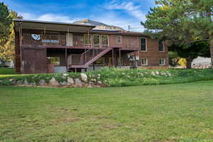 Back of house with a yard, stairway, brick siding, and a deck with mountain view