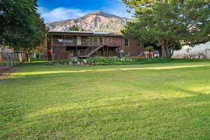 Back of property featuring stairs, a chimney, a mountain view, brick siding, and a balcony