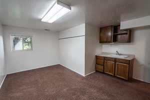 Bar area with light countertops, dark carpet, a textured ceiling, open shelves, and brown cabinets