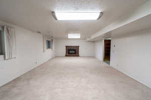 Unfurnished living room with a textured ceiling, a fireplace, and light carpet