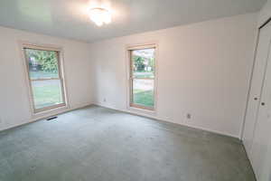 Carpeted spare room with a textured ceiling and baseboards