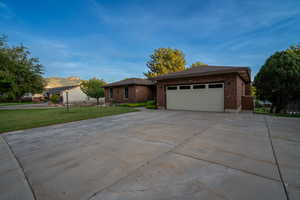 Ranch-style home featuring brick siding, a garage, driveway, a mountain view, and a front lawn