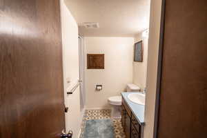 Full bath with vanity, a textured ceiling, and a stall shower