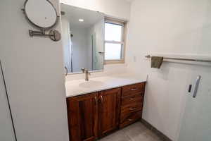 Full bath with vanity, a shower stall, and light tile patterned floors