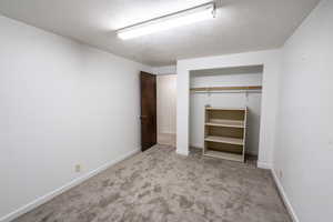 Unfurnished bedroom with light carpet, a textured ceiling, and a closet