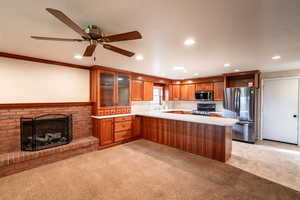 Kitchen with recessed lighting, appliances with stainless steel finishes, light countertops, glass insert cabinets, and light carpet
