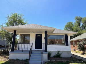 View of front of house with a shingled roof and covered porch