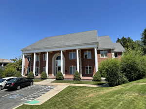 View of front facade featuring a porch, a front lawn, brick siding, and a shingled roof