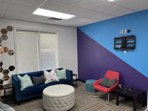 Sitting room with a drop ceiling and carpet floors