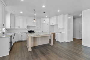 Kitchen with backsplash, pendant lighting, dark wood finished floors, light stone countertops, and recessed lighting