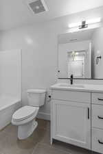 Bathroom featuring vanity, light tile patterned flooring, bathtub / shower combination, and a textured ceiling