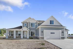 Craftsman-style home with stone siding, driveway, covered porch, and a shingled roof