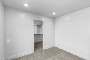 Unfurnished bedroom featuring light colored carpet, a spacious closet, and recessed lighting
