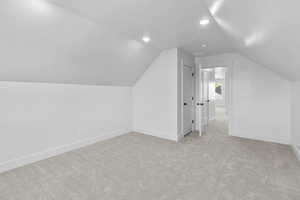 Additional living space featuring a textured ceiling, light carpet, and vaulted ceiling