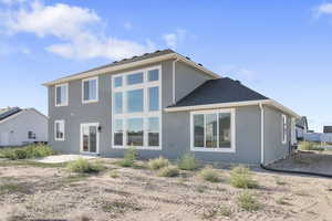 Rear view of house featuring a patio area, stucco siding, and roof with shingles