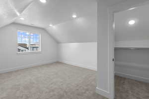 Bonus room with light carpet, a textured ceiling, vaulted ceiling, and recessed lighting
