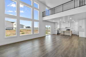 Unfurnished living room with dark wood-style floors, a towering ceiling, and recessed lighting