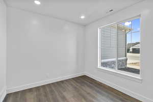 Empty room featuring dark wood finished floors and recessed lighting