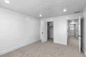Unfurnished bedroom featuring light carpet, recessed lighting, and a spacious closet