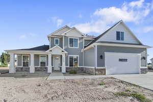 Craftsman house featuring stone siding, concrete driveway, and a porch