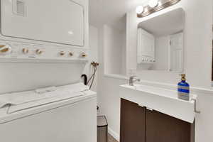 Downstairs Bathroom featuring stacked washing machine and dryer and vanity