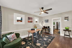 Living area into dining area with healthy amount of natural light, dark wood-type flooring, and a ceiling fan