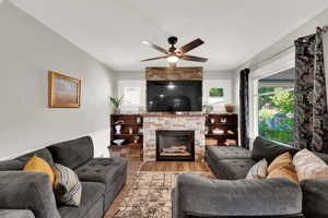 Living area featuring wood finished floors, a gas fireplace, and ceiling fan new windows throughout.