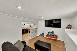 Downstairs Living area with light wood finished floors, a textured ceiling, recessed lighting, and bar. Perfect for basement rental with separate entrance.