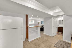 Downstairs Kitchen featuring freestanding refrigerator, light tile patterned floors, wood counters, recessed lighting, and open shelves
