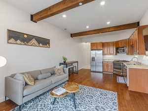 Living area with dark wood-style floors, beamed ceiling, and recessed lighting