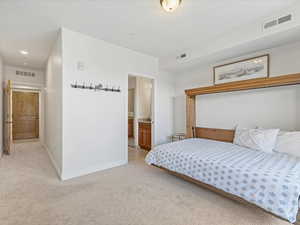 Carpeted bedroom with ensuite bathroom and recessed lighting