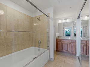 Bathroom with combined bath / shower with glass door, light tile patterned flooring, and vanity