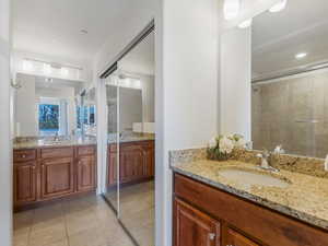 Bathroom with two sinks, vanity, light tile patterned flooring, and a stall shower