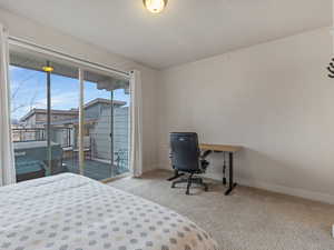 Bedroom with light carpet, a desk, and access to exterior