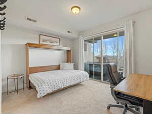 Carpeted bedroom with access to outside and an office area
