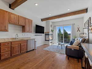 Living area with beam ceiling, a multi sided fireplace, recessed lighting, and dark wood finished floors