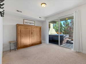 Unfurnished bedroom with light carpet and access to outside