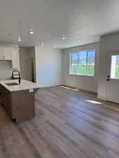 Kitchen featuring open floor plan, white cabinets, a kitchen island with sink, dark wood-style floors, and a textured ceiling
