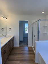 Bathroom with a shower stall, dark wood finished floors, a textured ceiling, and a bath