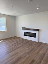 Unfurnished living room featuring a glass covered fireplace, dark wood finished floors, and a textured ceiling