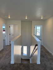 Stairway featuring carpet flooring and a textured ceiling