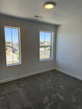 Unfurnished room featuring dark colored carpet and a textured ceiling