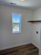 Washroom with dark wood-type flooring, hookup for a washing machine, and a textured ceiling